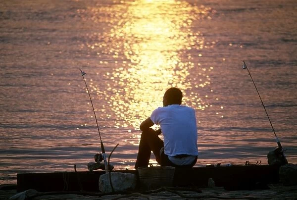 MISSISSIPPI RIVER: FISHING. A man seated between fishing poles beside the Mississippi River in St. Louis, Missouri, near sunset. Photographed c1974