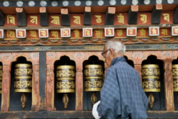 Buy Old Bhutanese man turning prayer wheels in Buddhist temple