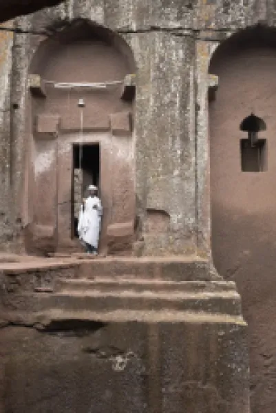 Buy A priest stands at the entrance to the rock-hewn church