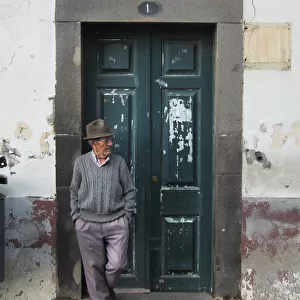 Old man in trilby leans against a doorway, Funchal, Maderia