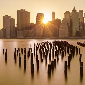 Lower Manhattan skyline, New York skyline, exposed wooden pier stumps, at sunset