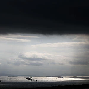 Cargo ships are seen sailing under storm clouds at open sea near the port of Piraeus