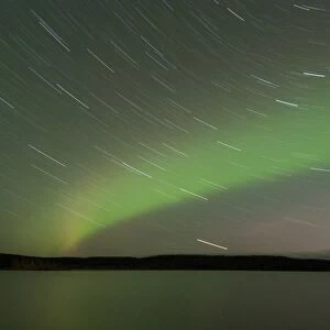 Aurora Borealis and star trails over lake at night, Muonio, Lapland, Finland, September