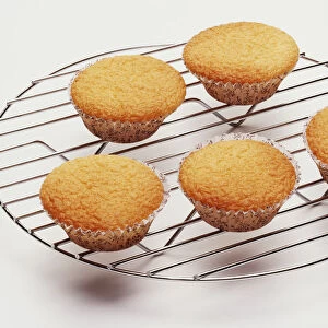 A wire cooling rack holding five fairy cakes
