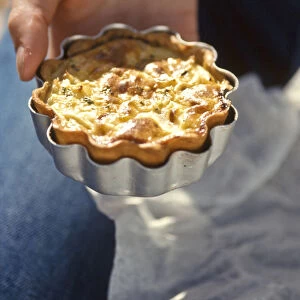 Home made quiche in its tin held in the hand credit: Marie-Louise Avery / thePictureKitchen