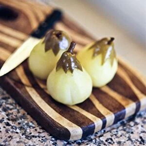 Peeled pears poached in vanilla sugar syrup on striped wooden board credit: Marie-Louise