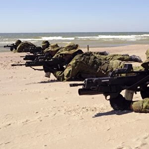 Lithuanian Special Forces members lie in formation on a beach