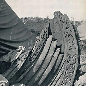 The Oseberg ship in the mound, showing the carving on stem and railing, 1935