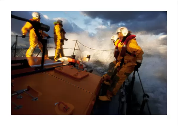 Crew members stood at the bow of the Berwick-upon-Tweed Mersey class lifeboat Joy and Charles Beeby 12-32, lots of spray