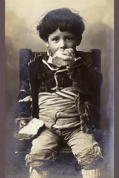 A poor young boy tucking into a hunk of bread - Italy