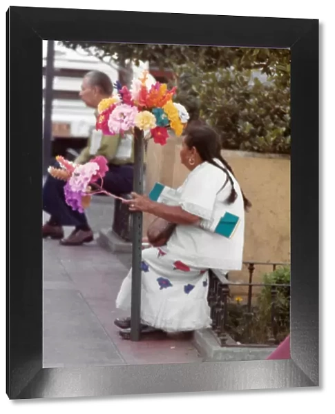 Mexican woman sitting with paper tissue flower arrangments