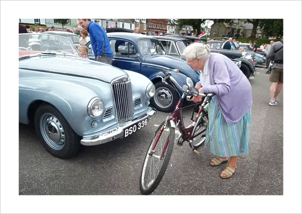 An old lady stops to look closely at a vintage motor car