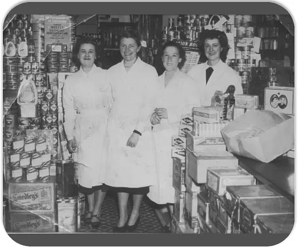Four shop workers line up for a photograph in a well-stocked grocery store