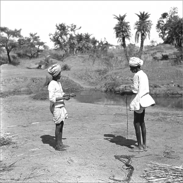 Two Men tie reeds by a stream