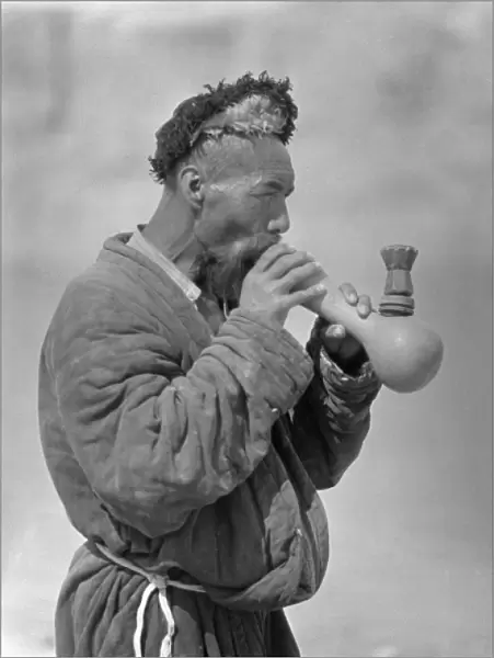 A Uyghur man smoking an elaborate pipe
