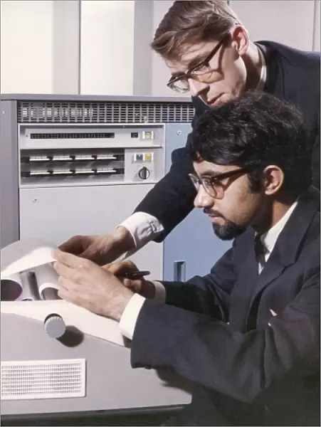 Two technicians check a computer printout