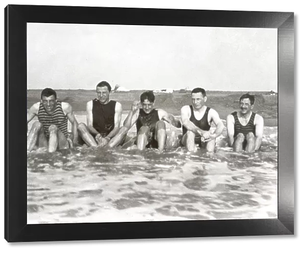 Five men sitting in the sea in bathing suits