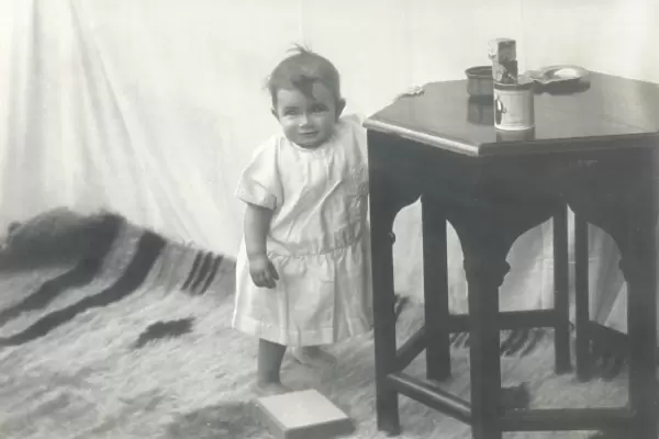 Smiling toddler leaning against a table