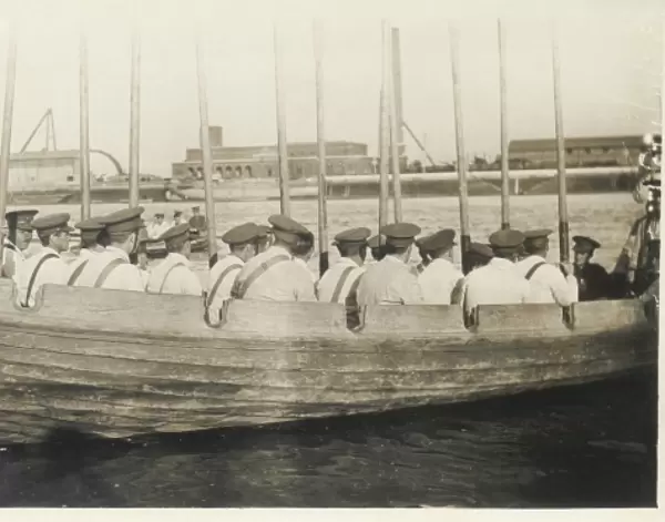 Ships crew in rowing boat with oars held vertically
