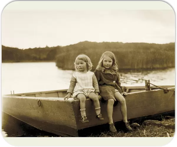 Two little girls sitting on the edge of a boat, Scotland