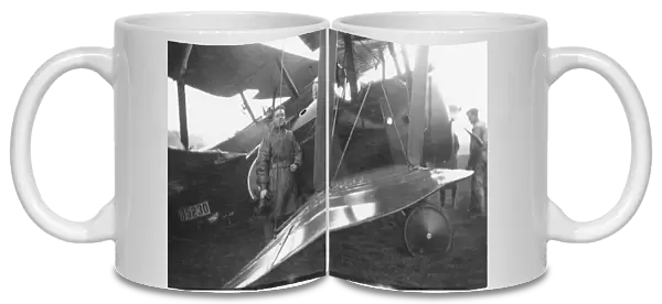 Pilot standing with biplane on an airfield, WW1