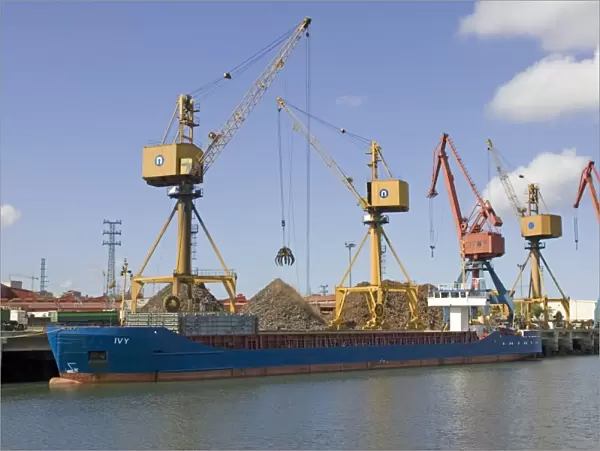 Cranes on quayside unloading scrap metal from cargo shipsinto trucks for reprocessing Bilbao docks Spain