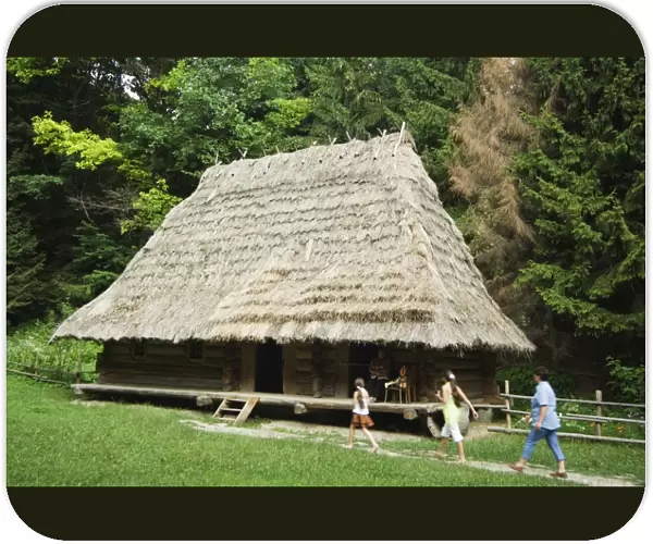 Tourists visiting traditional thatched roof house in