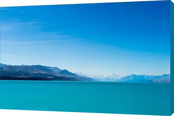 A turquoise blue lake with snow covered mountains in the distance, South Island, New Zealand