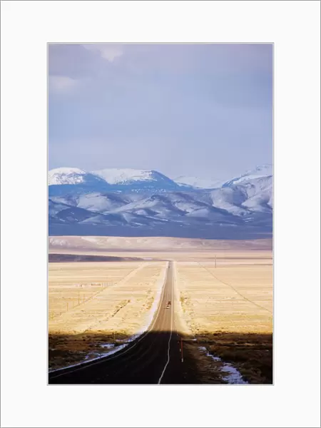 Snow capped mountains on a straight road of American south west, U