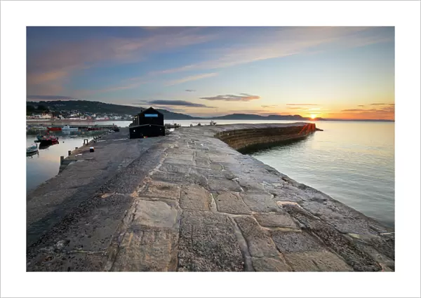 The Cobb with the cliffs of Jurassic Coast at sunrise, Lyme Regis, Dorset, England