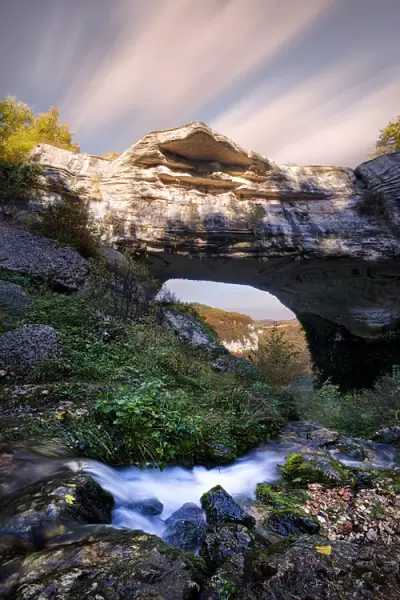 Waterfall flowing below Veja bridge, a huge natural arch in Lessinia, Veneto, Italy