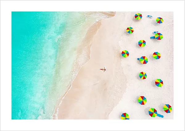 Aerial view of woman in bikini sunbathing on a tropical beach next to colorful umbrellas, Antigua, West Indies, Caribbean, Central America