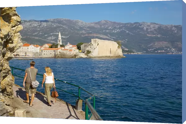 Couple walking along coast towards Old Town, Budva, Montenegro, Europe