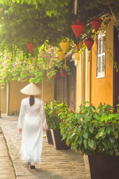 Woman wearing Ao Dai dress walking along street, Hoi An (UNESCO World Heritage Site)