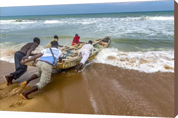 Africa, Benin, Grand Popo. A group of fishermen taking their boat into the water