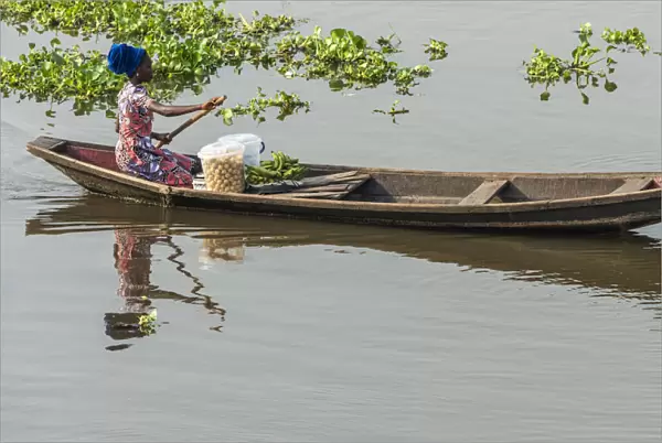 Africa, Benin, Lake Nokoua. A woman on the way to the market in the famous stilt
