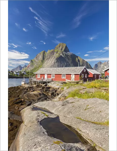 Typical houses of fishermen called Rorbu framed by rocky peaks and blue sea Reine