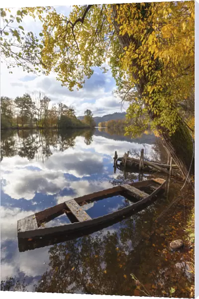 A wooden rowing boat in autumn on the Dordogne River, Correze, Nouvelle-Aquitaine