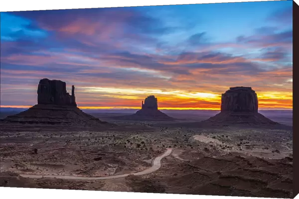 The Mittens against cloudy sky at sunrise, Monument Valley, Arizona, USA