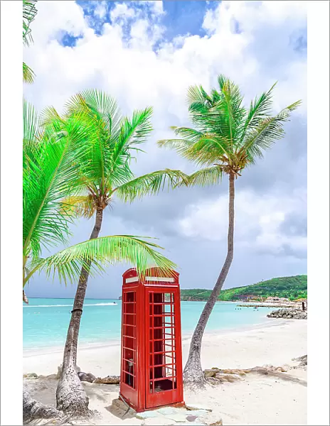 Red telephone box on the palm fringed Dickenson beach, Antigua, Antigua & Barbuda, Caribbean, West Indies