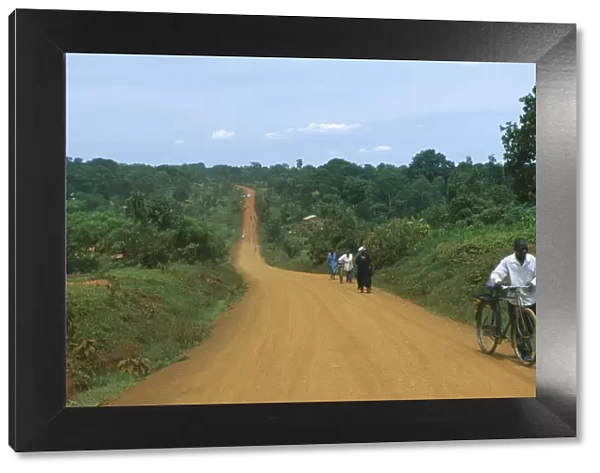 20069767. UGANDA Road Murram dirt road stretching into distance with cyclist approaching