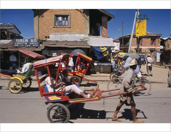 20079229. MADAGASCAR Antsirabe Rickshaws with passengers traveling along road