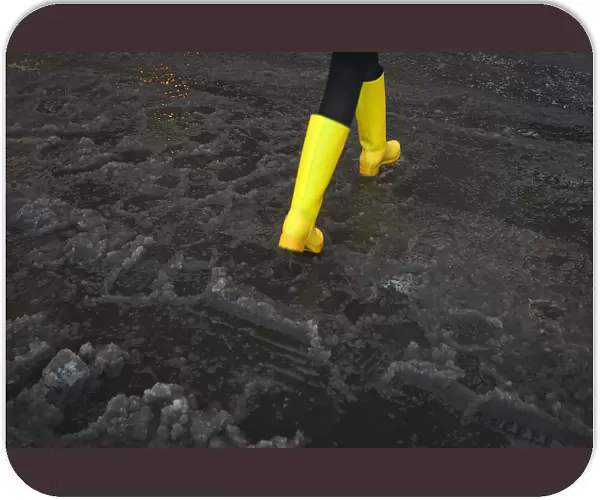 A woman with bright yellow boots walks though puddle of slush in Times Square during