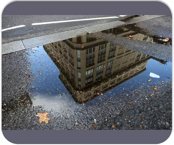 The offices of British life insurer Prudential are reflected in a puddle in London