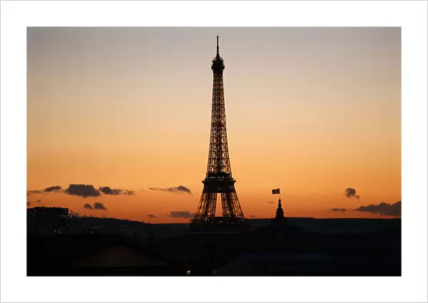 The Eiffel Tower is seen in silhouette at sunset in Paris