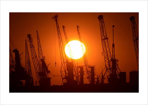 Cranes of German shipyard Blohm&Voss are silhouetted during sunset in Hamburg
