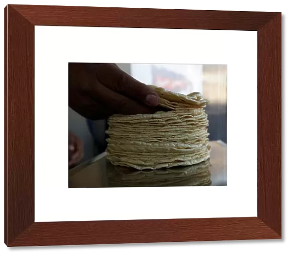 Person weighs a stack of freshly made corn tortillas at a tortilla factory in Mexico City