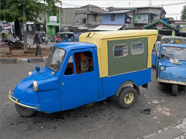 Blue tuk tuk three-wheeler vans on road in city, Manggarai District, Jakarta, Java, Indonesia, December