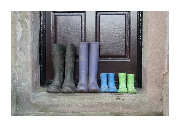Four pairs of wellington boots, two children's pairs, one women's pair and men's pair, outside farmhouse door, Whitewell, Lancashire, England, december