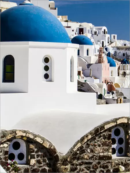 Oia, Greece. Row of Greek Orthdox Churches with blue domes and painted pastel white